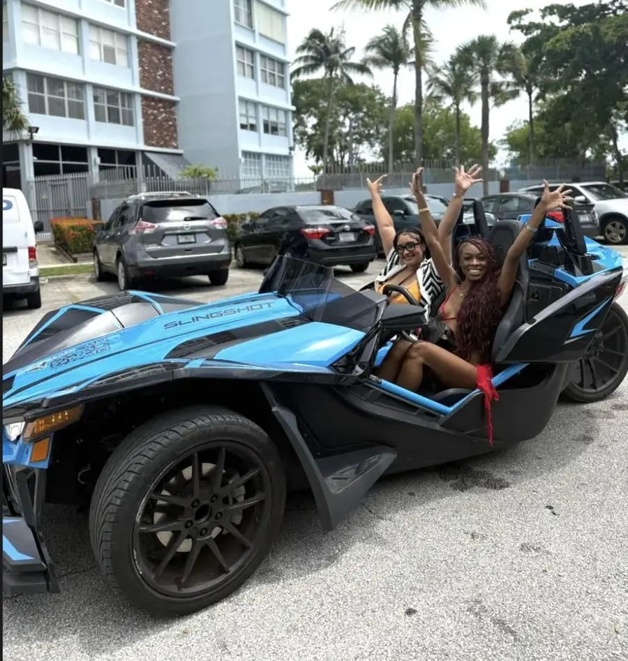 Blue Polaris Slingshot rental Miami Beach — two friends celebrating